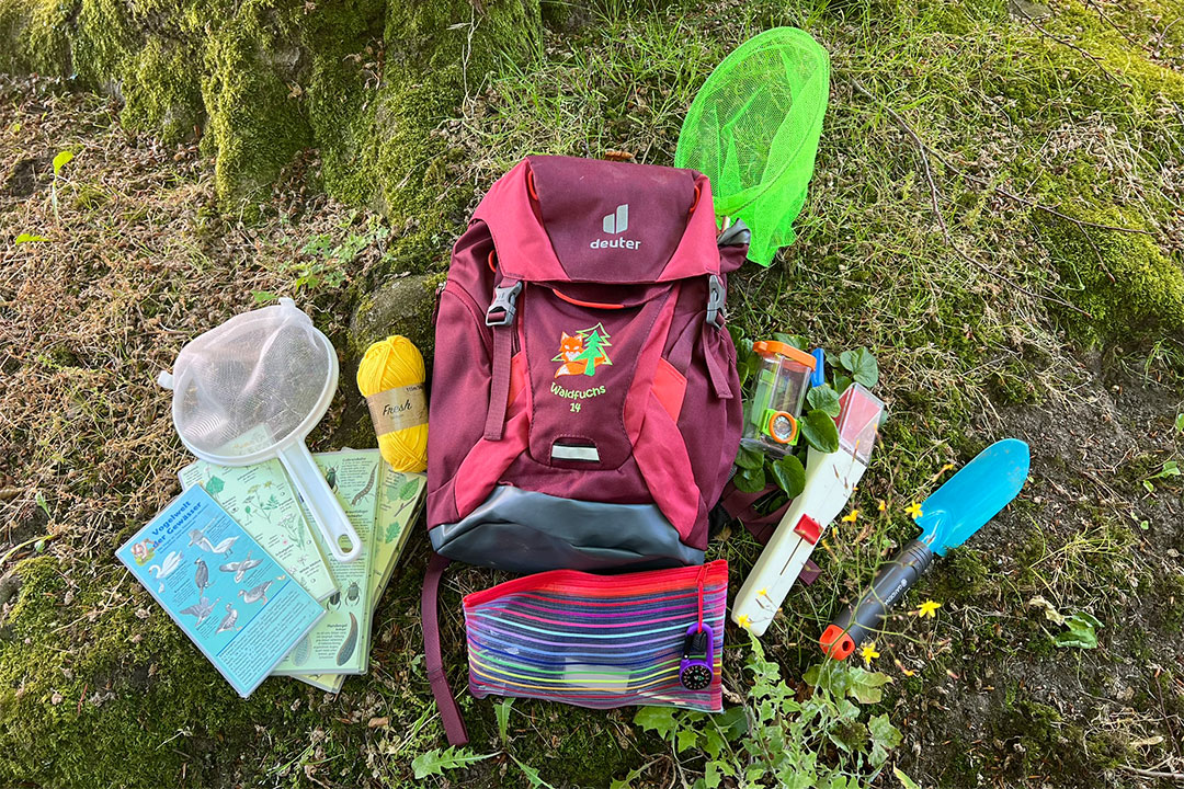 Forscherrucksack für Kinder mit rundherum ausgebreitetem Inhalt